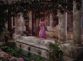 Movie still from “Quo Vadis” (1951), directed by Anthony Mann – A woman in a pink dress standing on steps; Extreme Wide shot, High angle