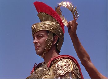 Movie still from “Quo Vadis” (1951), directed by Anthony Mann – A man in a roman soldier's outfit holding up a feather; Close Up shot, Low angle