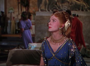 Movie still from “Quo Vadis” (1951), directed by Anthony Mann – A woman in a blue dress and a gold necklace; Medium shot, Over the shoulder angle
