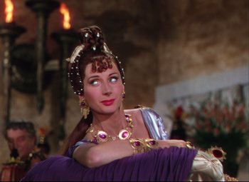 Movie still from “Quo Vadis” (1951), directed by Anthony Mann – A woman in a purple dress and a gold necklace; Close Up shot, Over the shoulder angle