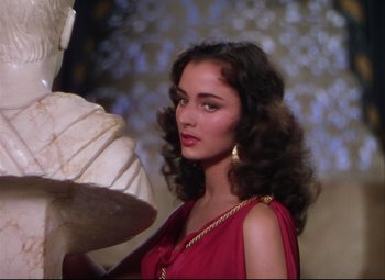 Movie still from “Quo Vadis” (1951), directed by Anthony Mann – A beautiful woman in a red dress holding an umbrella; Medium shot, Over the shoulder angle