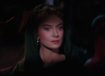 Movie still from “Quo Vadis” (1951), directed by Anthony Mann – A woman wearing a green head covering and earrings; Close Up shot, Over the shoulder angle