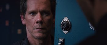 Movie still from “R.I.P.D.” (2013), directed by Robert Schwentke – A man's face with a combination lock on the wall behind him; Close Up shot, High angle