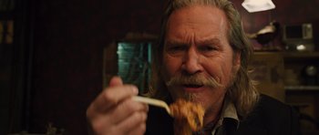 Movie still from “R.I.P.D.” (2013), directed by Robert Schwentke – An older man with long blond hair and a mustache is holding a piece of food; Close Up shot, Over the shoulder angle