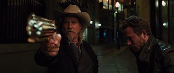 Movie still from “R.I.P.D.” (2013), directed by Robert Schwentke – A man in a cowboy hat holding a cell phone in his right hand; Medium shot, Over the shoulder angle
