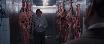 Movie still from “R.I.P.D.” (2013), directed by Robert Schwentke – A man standing next to a bunch of meat hanging in a room; Medium shot, Low angle