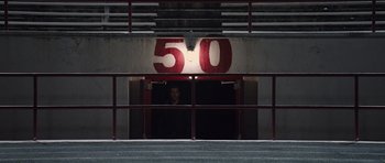 Movie still from “R.I.P.D.” (2013), directed by Robert Schwentke – A man standing in front of a door with a number 5 0 painted on it; Extreme Wide shot, High angle