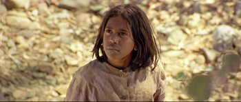 Movie still from “Rabbit-Proof Fence” (2002), directed by Phillip Noyce – A young girl is standing in front of a pile of rocks; Close Up shot, High angle