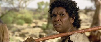 Movie still from “Rabbit-Proof Fence” (2002), directed by Phillip Noyce – A man holding a wooden stick in his hand; Close Up shot, Low angle