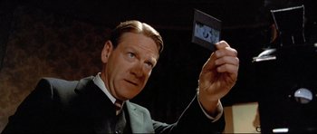 Movie still from “Rabbit-Proof Fence” (2002), directed by Phillip Noyce – A man in a black suit holding a picture; Close Up shot, Low angle