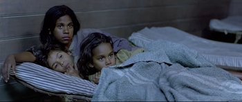 Movie still from “Rabbit-Proof Fence” (2002), directed by Phillip Noyce – A woman and a child laying in bed under a blanket; Close Up shot, High angle