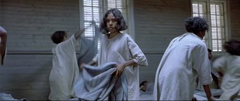 Movie still from “Rabbit-Proof Fence” (2002), directed by Phillip Noyce – A woman holding a blanket while standing next to a window; Medium shot, Low angle
