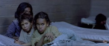 Movie still from “Rabbit-Proof Fence” (2002), directed by Phillip Noyce – A young girl laying in a bed next to a woman; Close Up shot, High angle