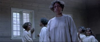 Movie still from “Rabbit-Proof Fence” (2002), directed by Phillip Noyce – A person standing in a room with other people; Medium shot, Low angle