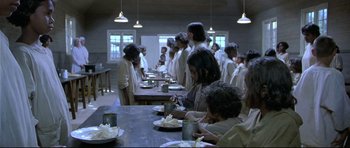 Movie still from “Rabbit-Proof Fence” (2002), directed by Phillip Noyce – A group of people sitting at a table with plates of food; Wide shot, High angle
