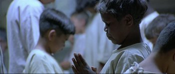 Movie still from “Rabbit-Proof Fence” (2002), directed by Phillip Noyce – A young boy is praying in front of a group of people; Close Up shot, Low angle