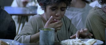 Movie still from “Rabbit-Proof Fence” (2002), directed by Phillip Noyce – A young boy sitting at a table eating rice; Close Up shot, High angle
