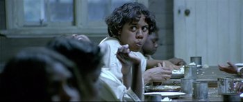 Movie still from “Rabbit-Proof Fence” (2002), directed by Phillip Noyce – A group of people sitting at a table eating food; Close Up shot, Low angle