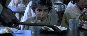 Movie still from “Rabbit-Proof Fence” (2002), directed by Phillip Noyce – A young boy sitting at a table with a bowl of food; Close Up shot, High angle
