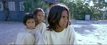 Movie still from “Rabbit-Proof Fence” (2002), directed by Phillip Noyce – A group of young people standing next to each other on a field; Close Up shot, High angle