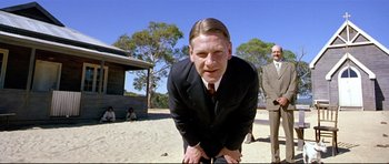 Movie still from “Rabbit-Proof Fence” (2002), directed by Phillip Noyce – A man in a business suit is crouching down; Medium shot, Low angle
