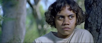 Movie still from “Rabbit-Proof Fence” (2002), directed by Phillip Noyce – A young person with curly black hair looking at the camera; Close Up shot, High angle