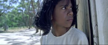 Movie still from “Rabbit-Proof Fence” (2002), directed by Phillip Noyce – A young girl with long black hair looking to her left; Close Up shot, High angle