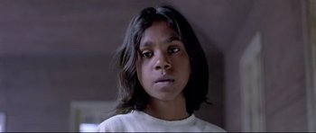Movie still from “Rabbit-Proof Fence” (2002), directed by Phillip Noyce – A young girl with long black hair stares into the camera; Close Up shot, High angle