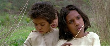 Movie still from “Rabbit-Proof Fence” (2002), directed by Phillip Noyce – A group of young people standing next to each other in the grass; Close Up shot, High angle
