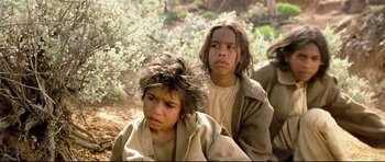 Movie still from “Rabbit-Proof Fence” (2002), directed by Phillip Noyce – A couple of people sitting next to each other on a field; Close Up shot, High angle