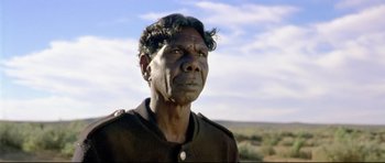 Movie still from “Rabbit-Proof Fence” (2002), directed by Phillip Noyce – An older man in a black shirt is looking into the distance; Close Up shot, Low angle