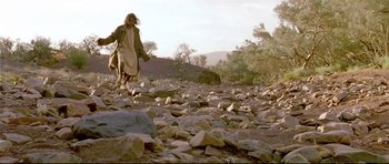 Movie still from “Rabbit-Proof Fence” (2002), directed by Phillip Noyce – A man walking on a rocky path in the wilderness; Wide shot, Low angle