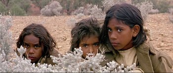 Movie still from “Rabbit-Proof Fence” (2002), directed by Phillip Noyce – A group of young children standing next to each other in a field; Close Up shot, High angle