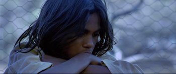 Movie still from “Rabbit-Proof Fence” (2002), directed by Phillip Noyce – A man with long hair is leaning on his hand; Extreme Close Up shot, Low angle