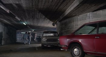 Movie still from “Rabid Dogs” (1974), directed by Mario Bava – A couple of cars parked in a parking garage; Wide shot, High angle