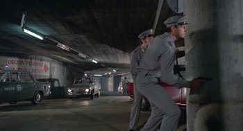 Movie still from “Rabid Dogs” (1974), directed by Mario Bava – A couple of men standing next to each other in a parking garage; Wide shot, Low angle
