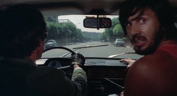 Movie still from “Rabid Dogs” (1974), directed by Mario Bava – Two men in a car driving down a street; Close Up shot, Over the shoulder angle