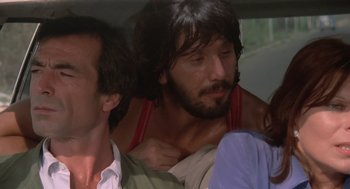Movie still from “Rabid Dogs” (1974), directed by Mario Bava – A man with a beard is sitting in the back of a car; Close Up shot, Over the shoulder angle