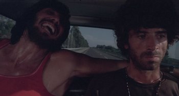 Movie still from “Rabid Dogs” (1974), directed by Mario Bava – Two men in the back seat of a car laughing; Close Up shot, Low angle