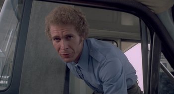 Movie still from “Rabid Dogs” (1974), directed by Mario Bava – A man in a blue dress shirt is leaning against a wall; Close Up shot, Low angle