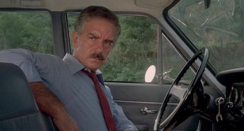 Movie still from “Rabid Dogs” (1974), directed by Mario Bava – A man sitting in the driver's seat of a car; Close Up shot, Low angle