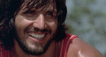 Movie still from “Rabid Dogs” (1974), directed by Mario Bava – A person with long hair smiling; Close Up shot, Low angle