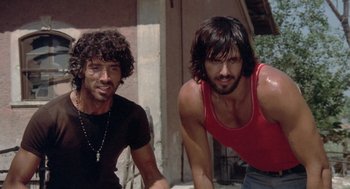 Movie still from “Rabid Dogs” (1974), directed by Mario Bava – Two young men sitting next to each other on a street; Close Up shot, Low angle