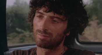 Movie still from “Rabid Dogs” (1974), directed by Mario Bava – Close up of a man with long hair and a beard; Close Up shot, Low angle