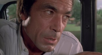 Movie still from “Rabid Dogs” (1974), directed by Mario Bava – A person wearing a white shirt; Close Up shot, Over the shoulder angle