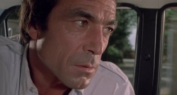 Movie still from “Rabid Dogs” (1974), directed by Mario Bava – A person in a car with trees in the background; Close Up shot, Low angle