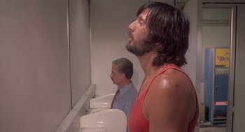 Movie still from “Rabid Dogs” (1974), directed by Mario Bava – Two men are standing in front of urinals in a restroom; Medium shot, Low angle