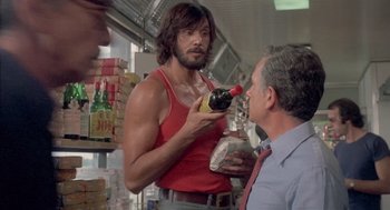 Movie still from “Rabid Dogs” (1974), directed by Mario Bava – A man in a red shirt is holding a banana; Medium shot, Low angle