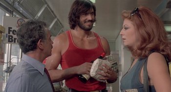 Movie still from “Rabid Dogs” (1974), directed by Mario Bava – A group of people standing around a man holding a bag of money; Medium shot, Low angle