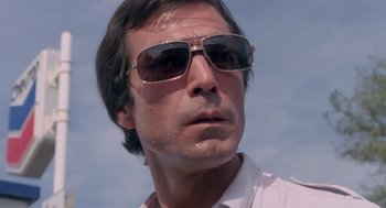 Movie still from “Rabid Dogs” (1974), directed by Mario Bava – A person wearing sunglasses; Close Up shot, Low angle